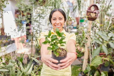 Portrait of a smiling young woman holding plants