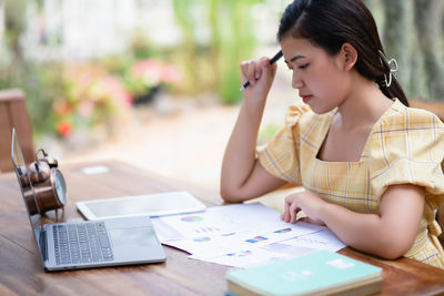 Woman using phone while sitting on table