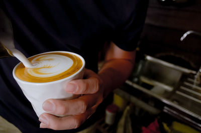 Midsection of man holding coffee cup