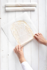 Cropped image of person holding paper against white wall