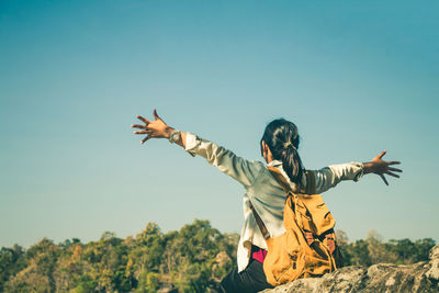 Woman with arms outstretched against clear sky