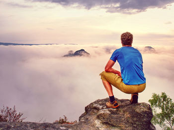 Autumnal misty morning in wild nature. sports wearing hiker on peak watching show in valley bellow