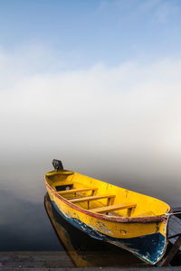 Fishing boat moored on sea against sky