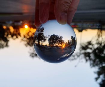 Reflection of person hand holding crystal ball on glass