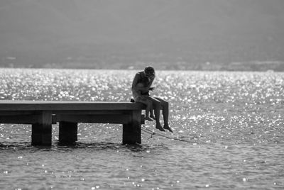 Woman sitting with son on pier over sea