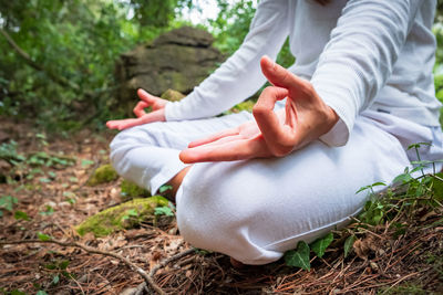 Midsection of woman meditating in forest