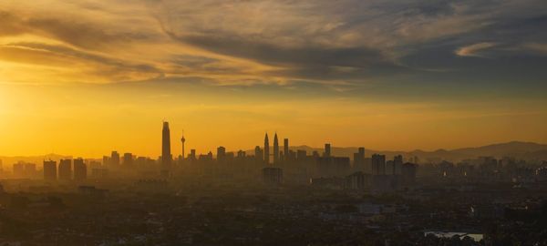 Buildings in city against sky during sunset