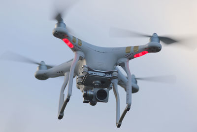 Full frame close up front view of a hovering quadcopter camera drone. plain sky background