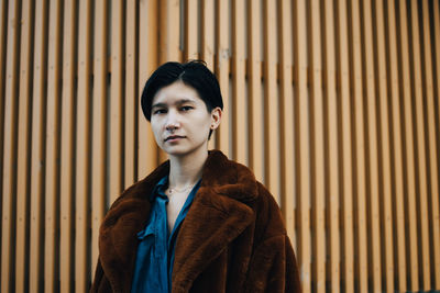 Portrait of woman standing against wooden wall