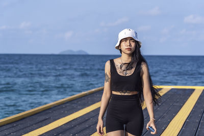 Portrait of young woman standing by sea against sky