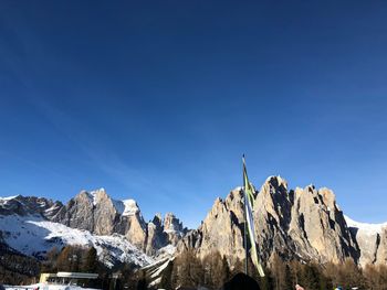 Low angle view of snowcapped mountains against clear blue sky