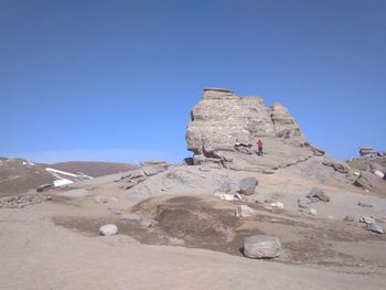 Rock formations on landscape against clear blue sky