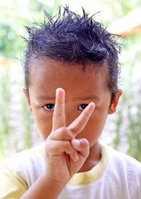Close-up portrait of boy gesturing peace sign