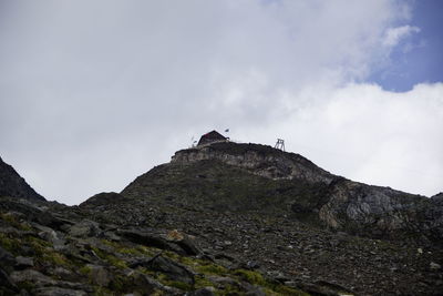 Low angle view of rocks on cliff against sky