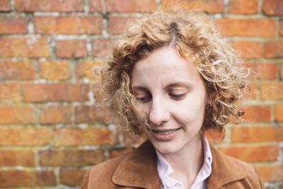 Woman looking down against brick wall