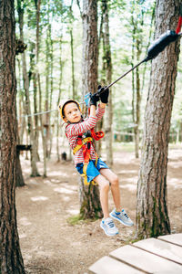 Woman by tree trunk in forest