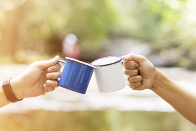 Cropped image of hands toasting coffee cup