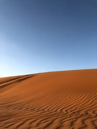 Sand dunes in desert against clear blue sky