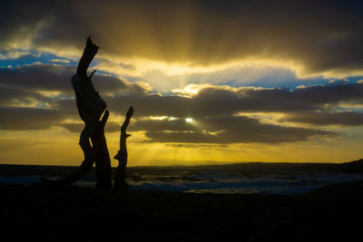 Silhouette person standing on beach against sky during sunset