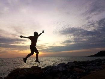 Silhouette man standing on beach against sky during sunset