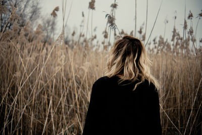 Rear view of woman standing on field against sky