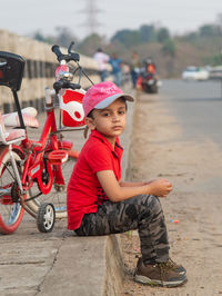 Boy alone sitting on roadside