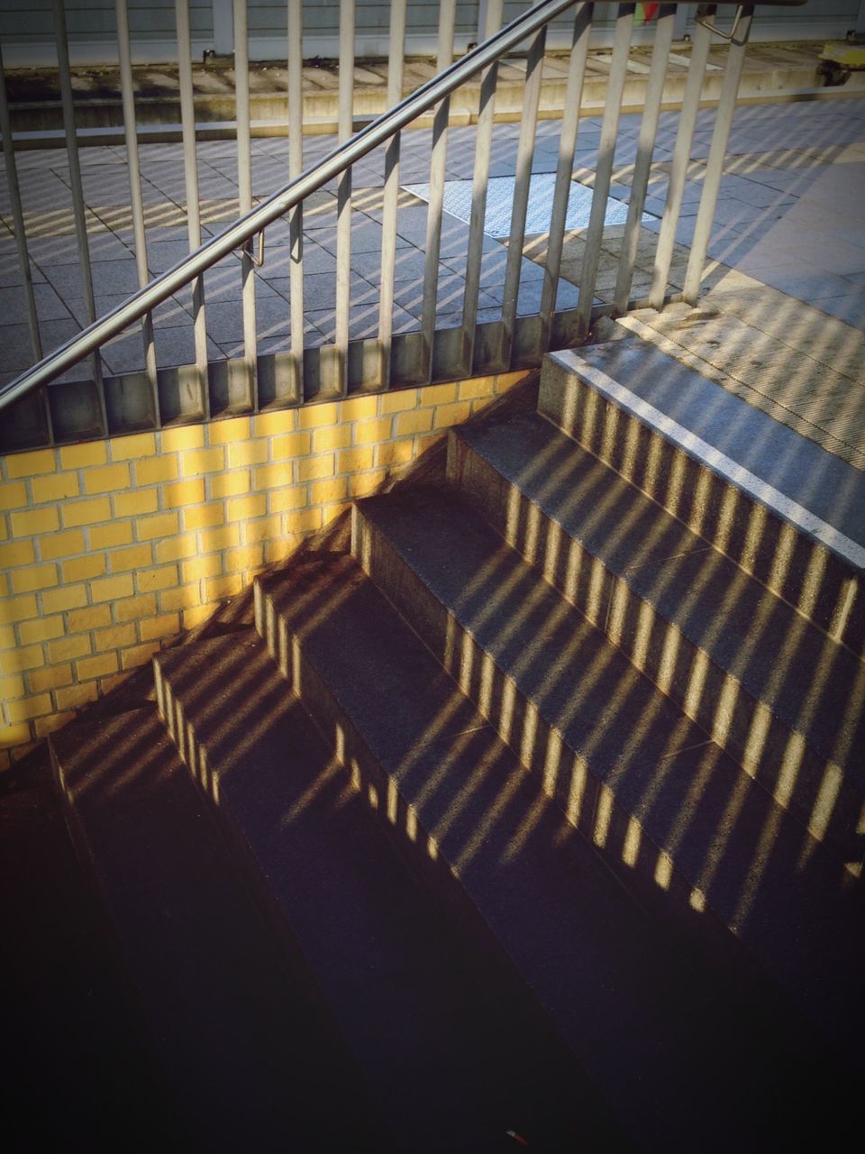 high angle view, shadow, sunlight, steps, railing, pattern, built structure, architecture, staircase, steps and staircases, building exterior, outdoors, in a row, empty, day, fence, footpath, metal, the way forward, street