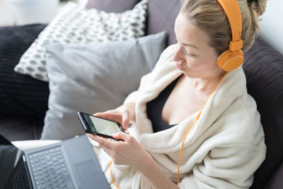 Midsection of woman holding mobile phone while sitting on sofa
