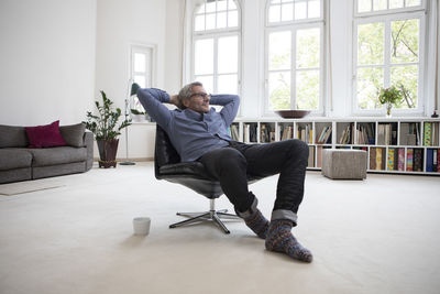 Relaxed mature man at home sitting in chair