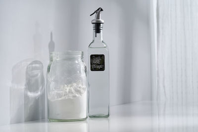 Close-up of glass bottle on table against wall