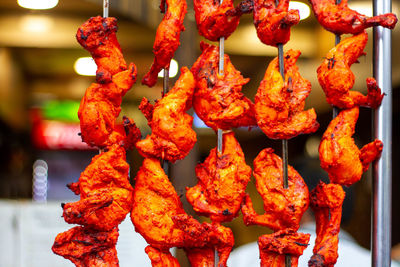 Marinated chicken thighs hanging on skewers in a restaurant window 