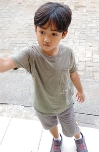 Portrait of cute boy standing on footpath