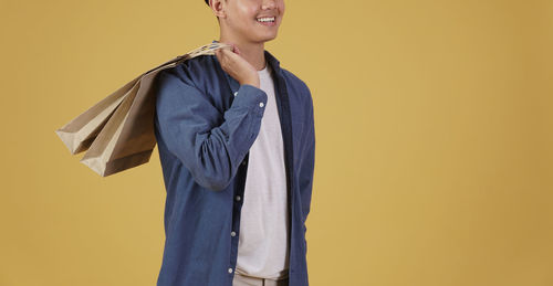 Woman looking away while standing against yellow background