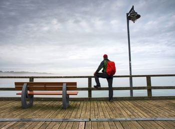 Man sitting on bench by wooden pier and watch calm sea. seabridge on ruegen island