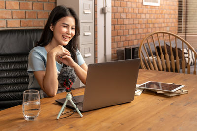 Young woman using mobile phone while sitting on table