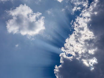 Low angle view of sunlight streaming through clouds