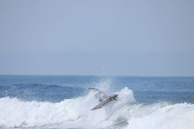 Waves splashing on sea against clear sky