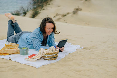 Portrait of young woman sitting on sand at beach