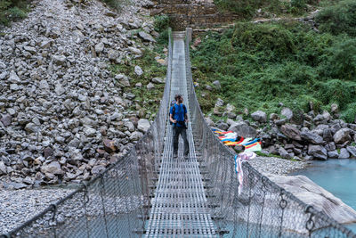 Male hiker standing on footbridge over river