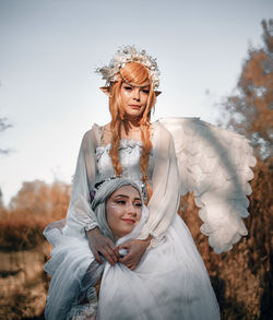 Young women wearing costume standing against trees