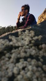 Low angle view of young man sitting on rock