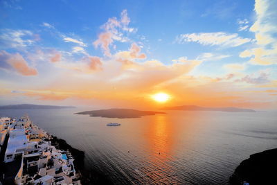 Scenic view of sea by city against cloudy sky during sunset