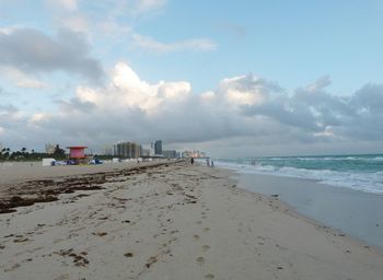 Beach by buildings against sky