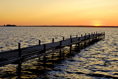 Pier over sea against sky during sunset