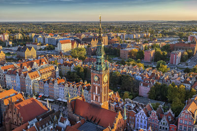 Town hall tower amidst buildings in city at sunset