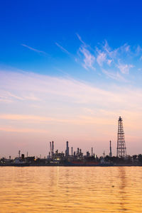 Sea by buildings against sky during sunset