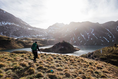 Rear view of woman walking on land against mountain