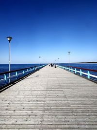 View of pier on sea against clear blue sky