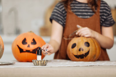 Midsection of woman with jack o lantern on table