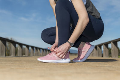 Female tying up laces on running shoes, preperation before jogging.